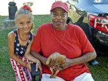 Rita Coleman, a grandmother from the North area, sits with her granddaughter Talia Stack, 7, and their 5 month-old puppy Lucky while they wait in patriotic attire for the fireworks in North.